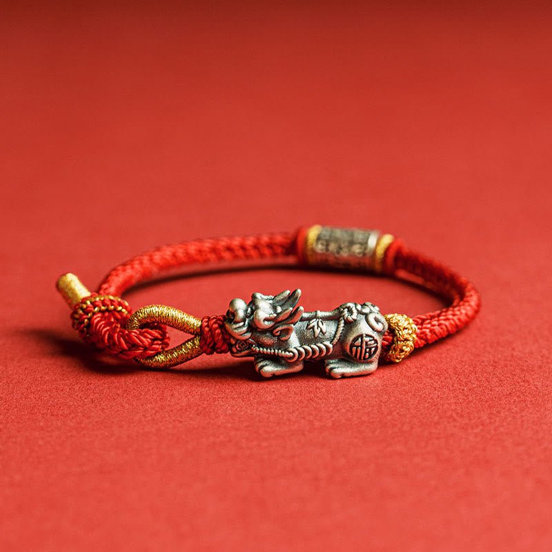 Sterling silver Pixiu red string bracelet side view with braided cord and engraved silver tube on red backdrop