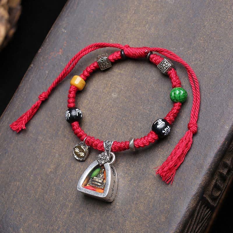 Red braided rope Amitabha Buddha protection bracelet with copper beads and tassel, top-down view on wooden surface