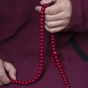 108 Abelia Biflora wood Buddhist prayer mala beads held in hands showing full strand with knotted tassel and deep red finish