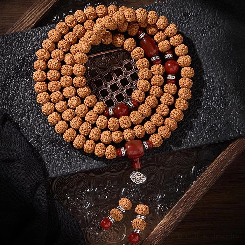 Full 108 bead mala necklace with bodhi seeds dzi bead and decorative tassel pendant on dark fabric