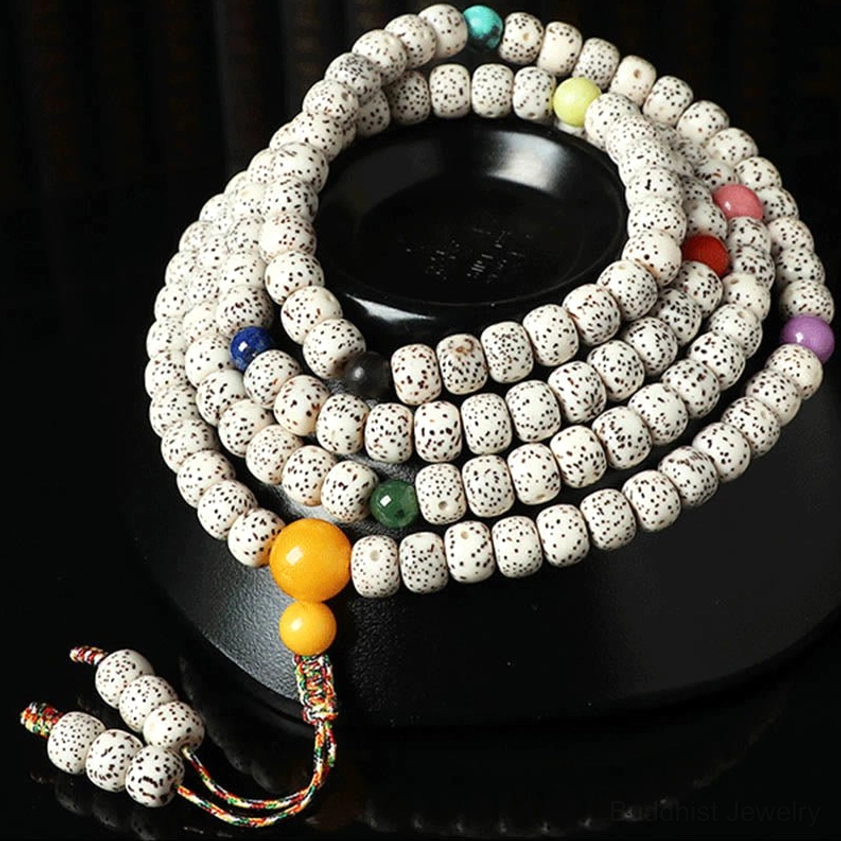 108-bead bodhi seed mala with colored spacer beads and braided tassel on black ceramic display stand