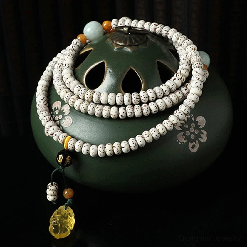 108-bead bodhi seed prayer beads mala with amber pendant and floral accents on green ceramic incense burner