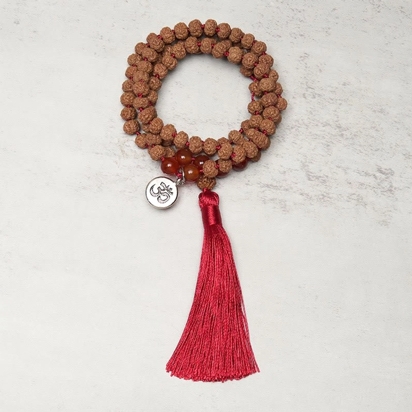 Authentic bodhi seed mala beads overhead view with sacred om metal charm and red silk tassel accent