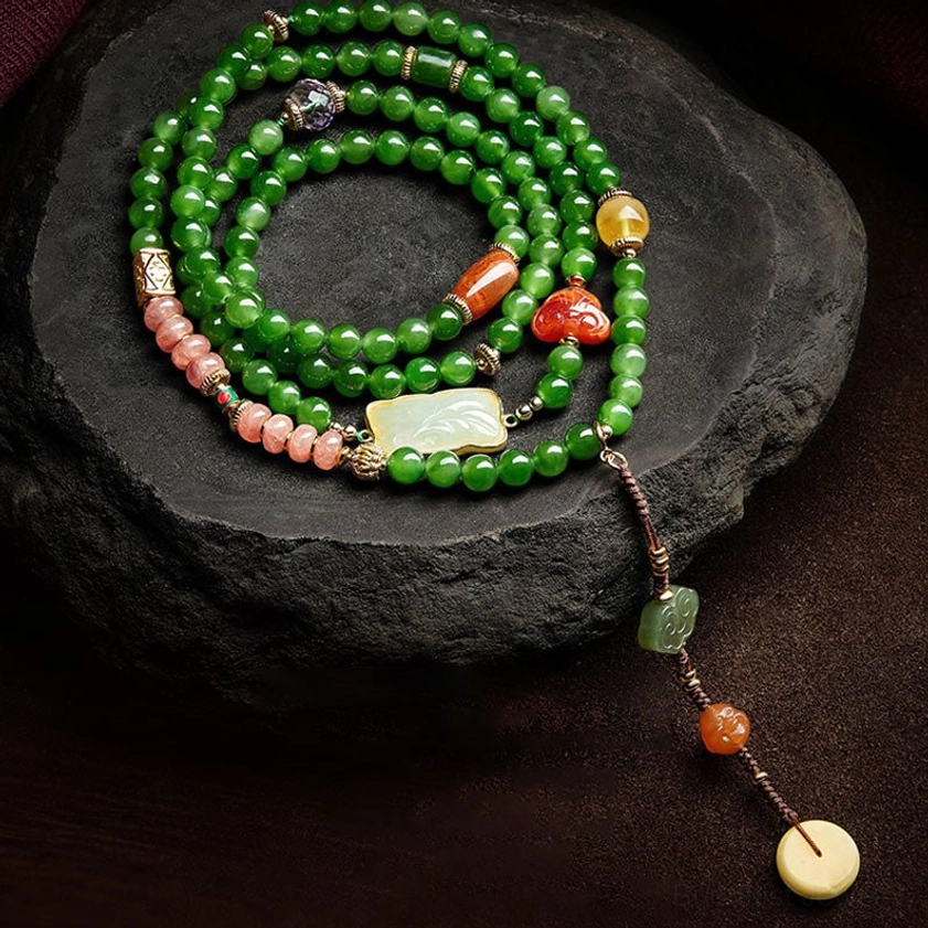 108 bead cyan jade red agate Buddhist prayer mala bracelet necklace with laughing Buddha pendant displayed on dark stone