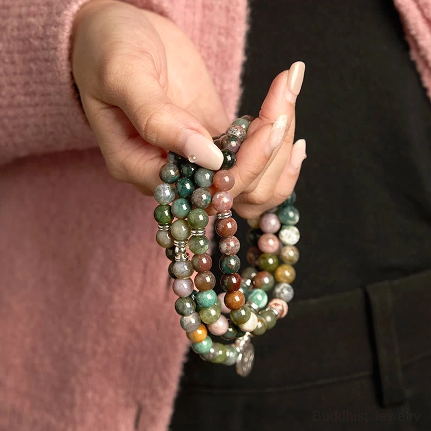 Woman's hand wearing 108-bead Indian agate mala bracelet with lotus metal pendant