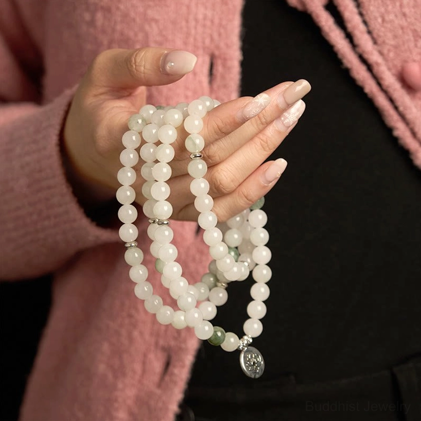 Medium close-up of jade mala prayer bracelet held in palms, showing 108 beads coiled design with visible lotus pendant