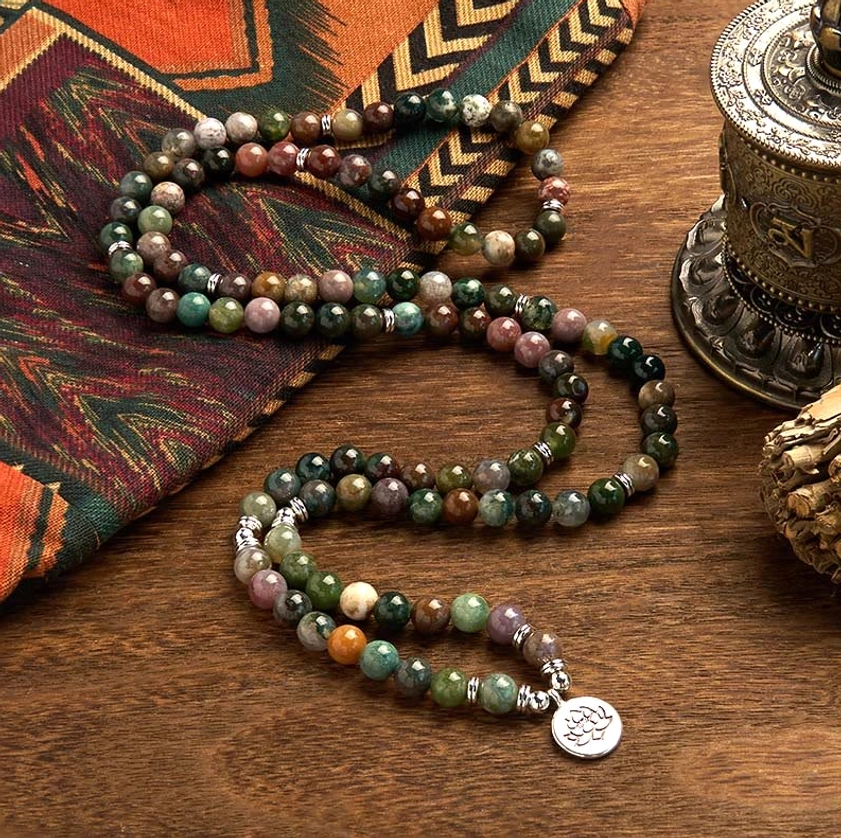 Handmade 108-bead Indian agate mala bracelet featuring natural stone beads and lotus metal pendant on ethnic textile
