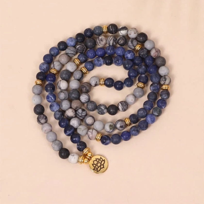 Spiritual 108 bead mala set showing mixed stone beads gold accents and hanging lotus charm on flatlay