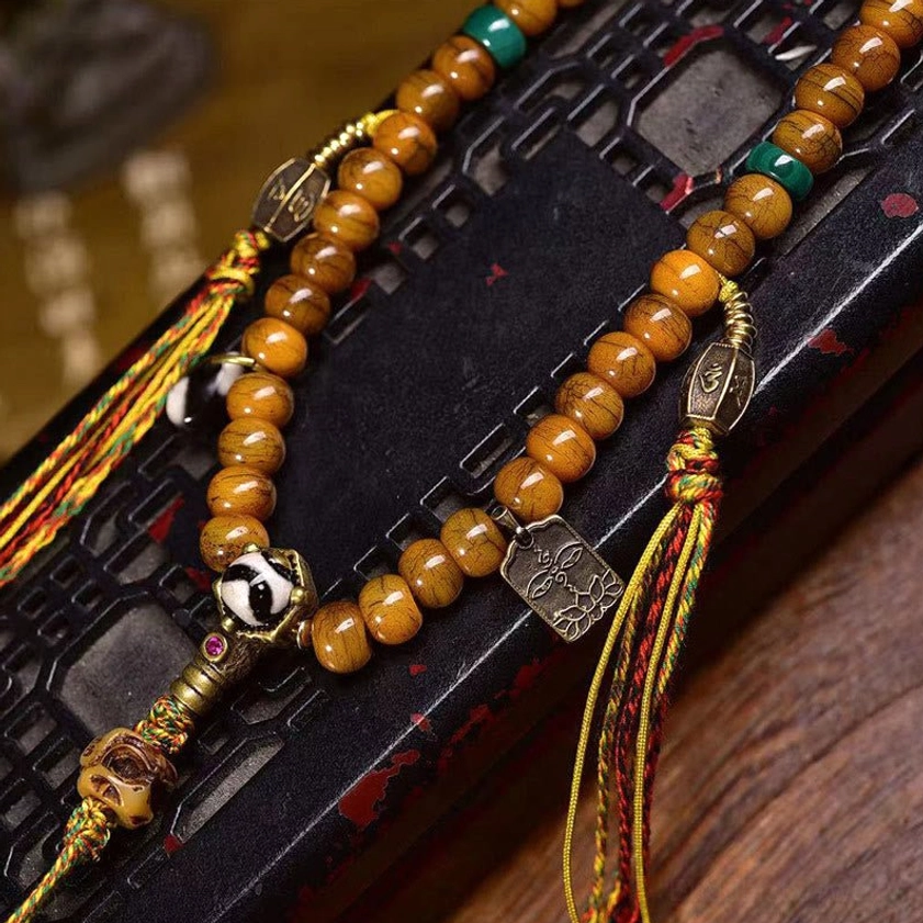 Single strand Buddhist prayer mala with brown barrel bone beads, turquoise and red spacer beads, silver skull guru bead, and woven tassel