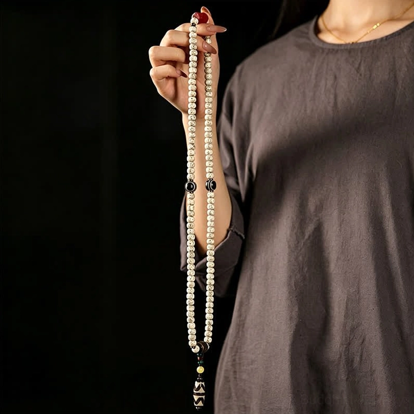 Full-length 108 bead Buddhist mala held by hand featuring striped Dzi bead pendant and complete prayer strand