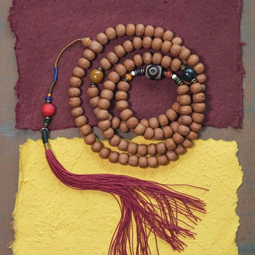 108 Buddhist prayer mala beads flat lay display showing complete necklace with brown seed beads, colorful accent beads, and red tassel