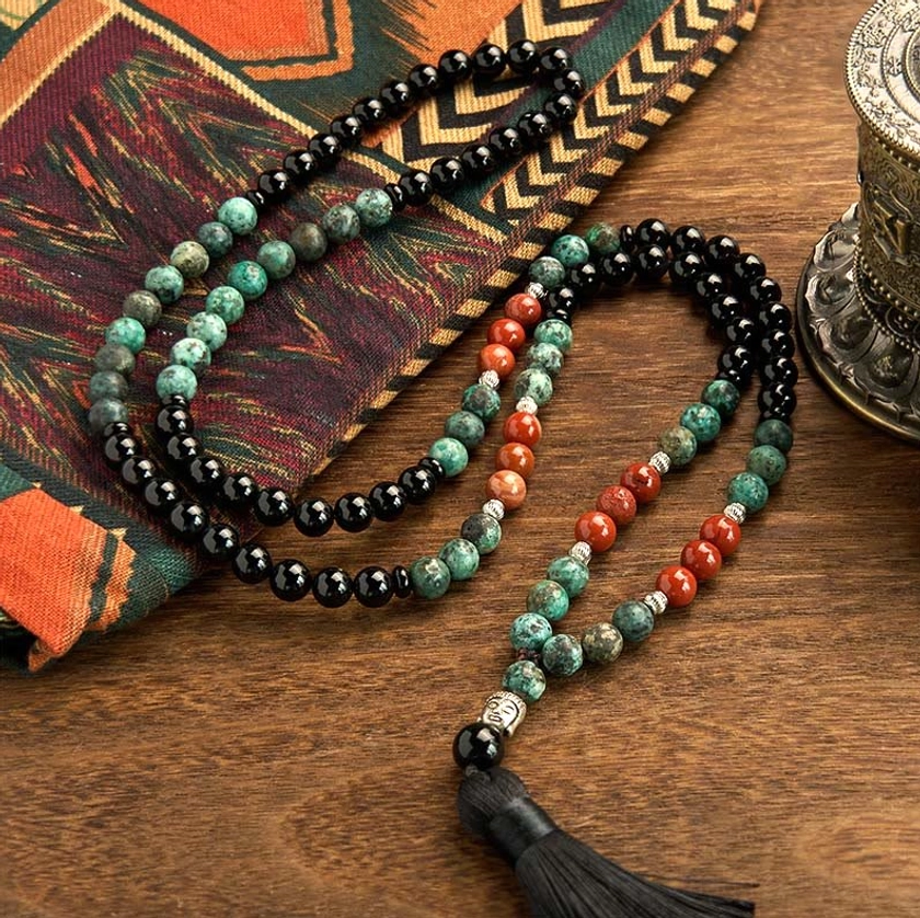 Long Buddhist mala necklace featuring 108 beads in natural black onyx, red jasper, and turquoise stones with decorative black tassel and Buddha head accent