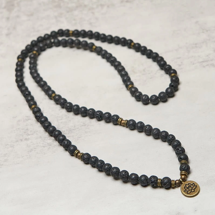Full-length 108 bead lava rock mala prayer necklace with lotus charm displayed on light gray surface