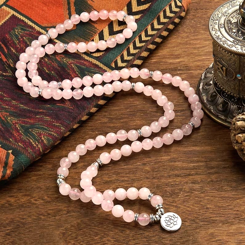 Rose quartz mala prayer beads with lotus charm on patterned fabric, complete mala strand view