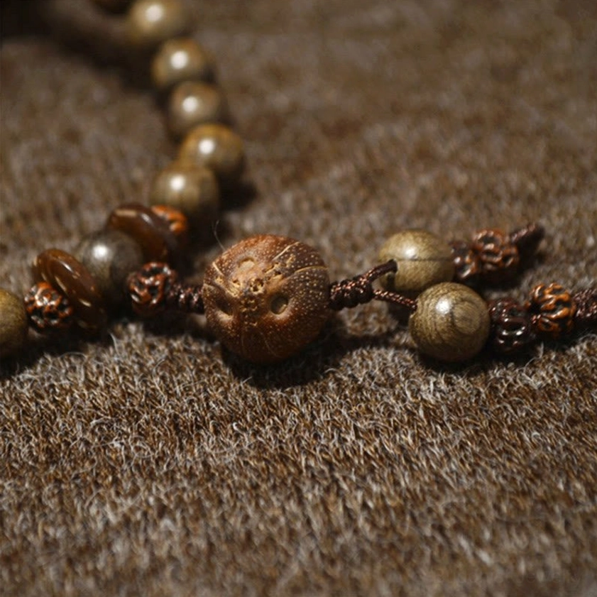 Sandalwood mala bracelet with 108 sacred prayer beads, featuring natural wood grain patterns and protective tassel, product detail shot