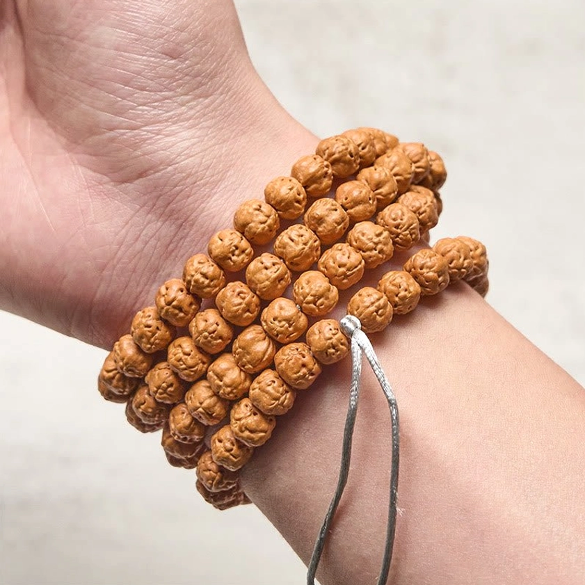 Bodhi seed prayer mala bracelet worn on human wrist showing wrapped brown beads with silver tassel hanging