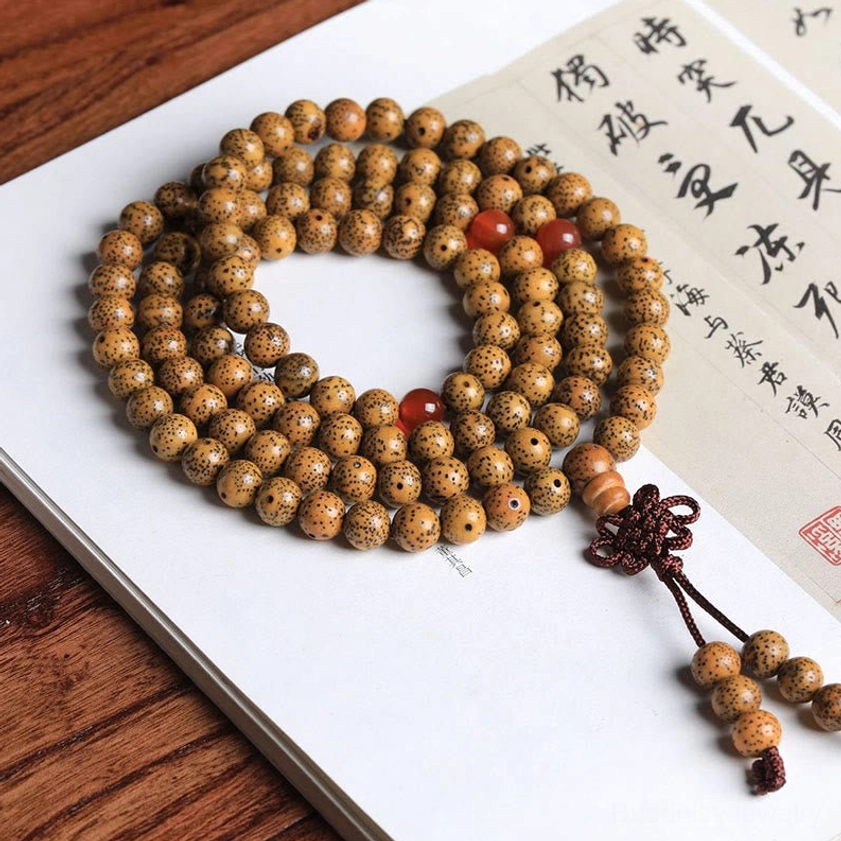 Authentic 108-count bodhi seed prayer mala beads flat lay with red agate accents on Chinese calligraphy paper, displaying complete Buddhist mala bracelet with knotted tassel