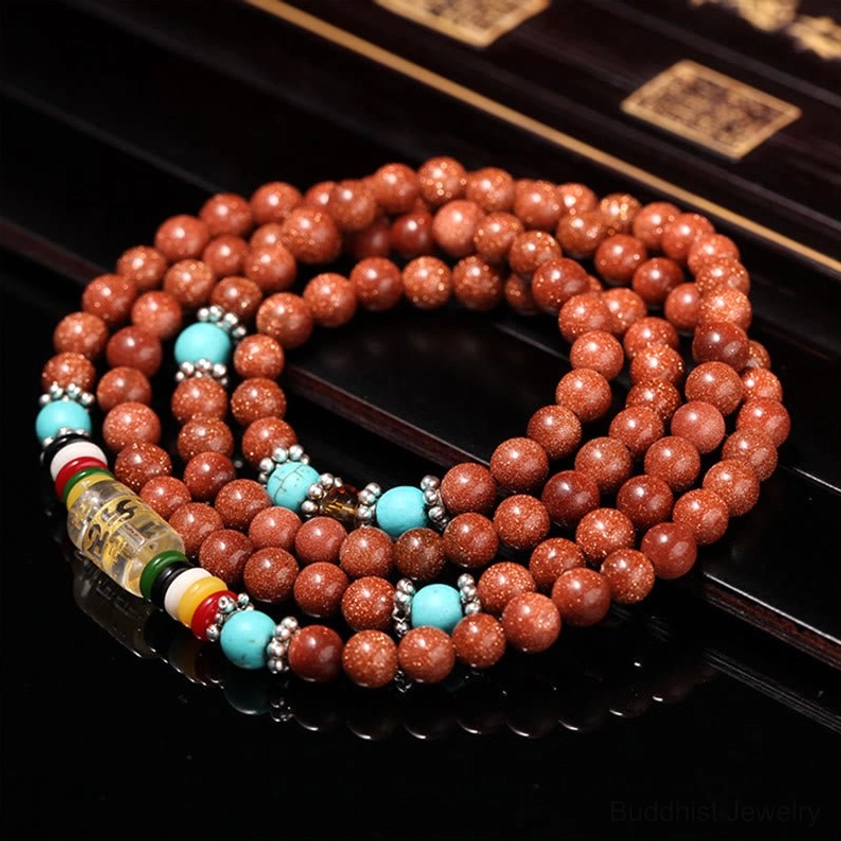 Full 108 goldstone mala bracelet in top-down flat lay showing complete decorative bead parts on dark wooden table