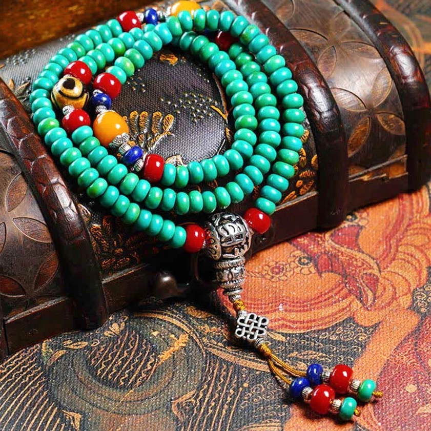 Complete 108-bead Buddhist mala prayer bracelet with gemstone accents displayed on vintage wooden surface