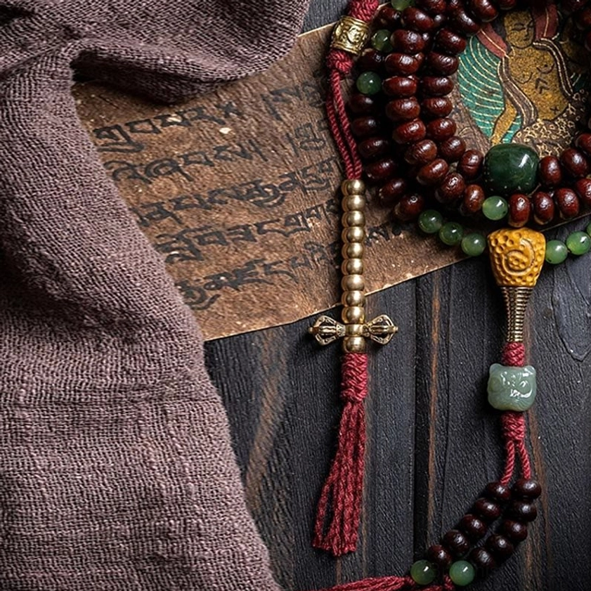 Buddhist prayer mala with copper dorje charm and red tassel detail in flat lay