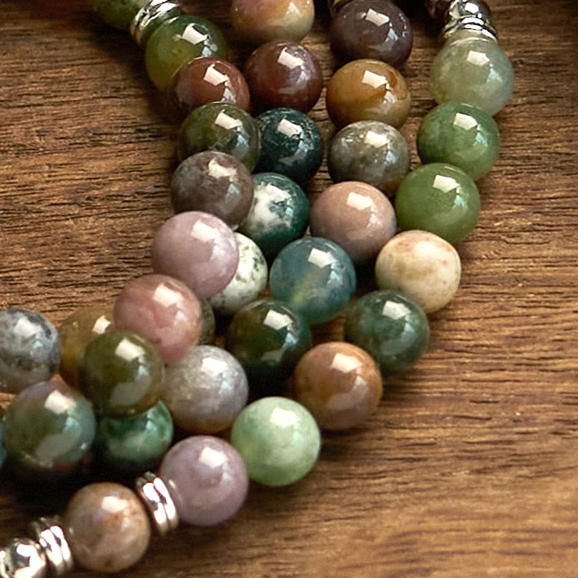 Close-up macro detail of 108-bead Indian agate mala bracelet showing natural stone texture and lotus pendant