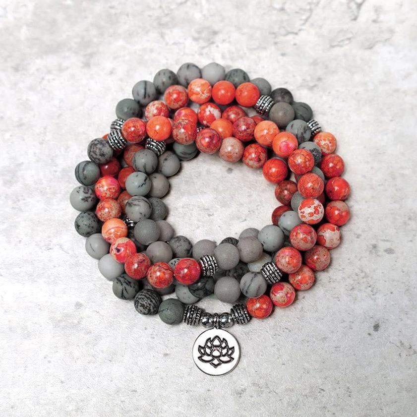 Buddhist prayer mala beads with gray and red jasper stones on textured background