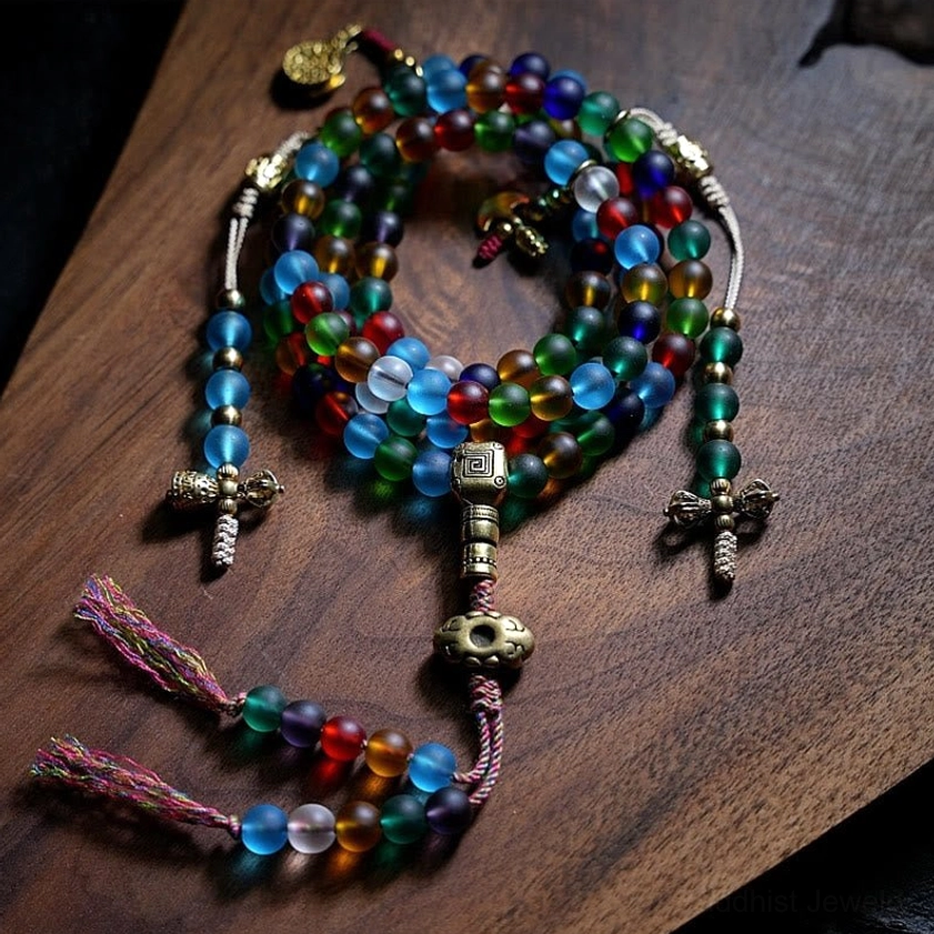 108 Liuli glass mala beads bracelet with multicolored frosted beads and vintage metal Buddhist charms, overhead flat lay on wooden surface