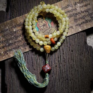 108 mala prayer beads overhead view with green tassel and thangka charm on Sanskrit background
