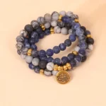 108 bead mala bracelet with sodalite zebra jasper and gold lotus charm on pink background