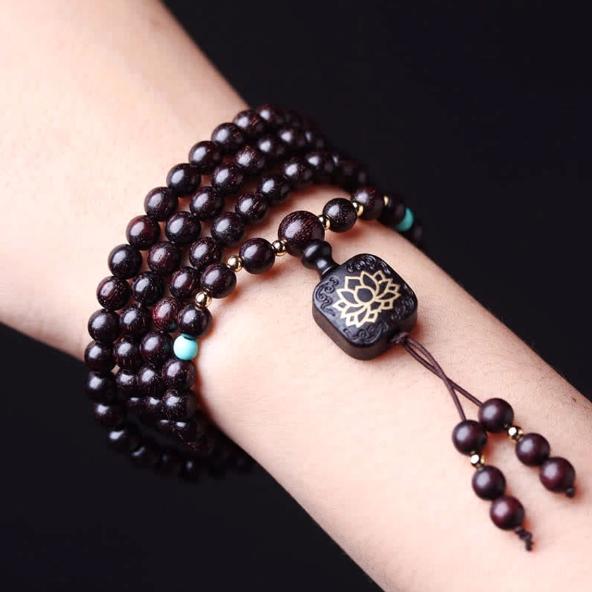 Red sandalwood mala bracelet worn on forearm showing multi-wrap design with lotus pendant and turquoise spacers
