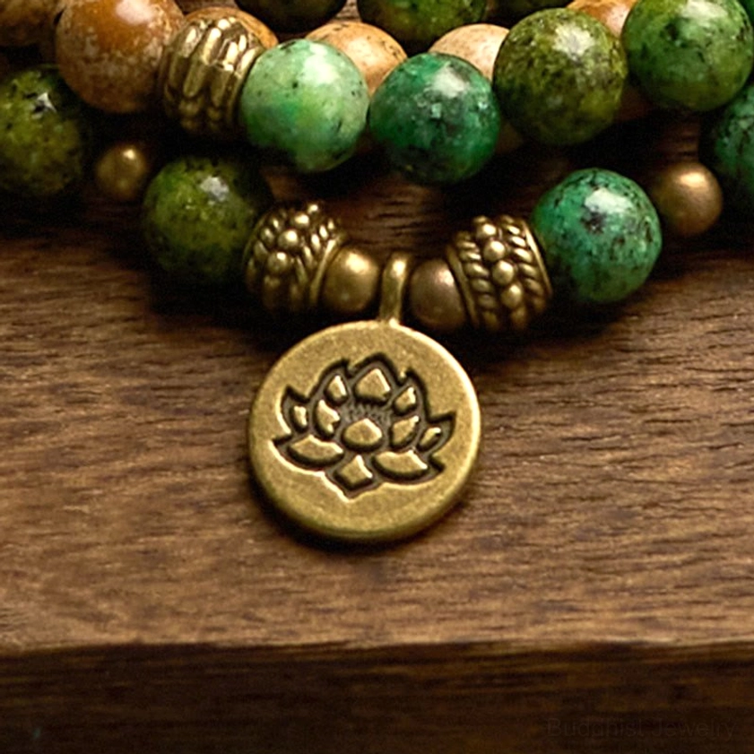 Close-up detail of embossed lotus metal charm pendant on Buddhist prayer mala bracelet with decorative accents