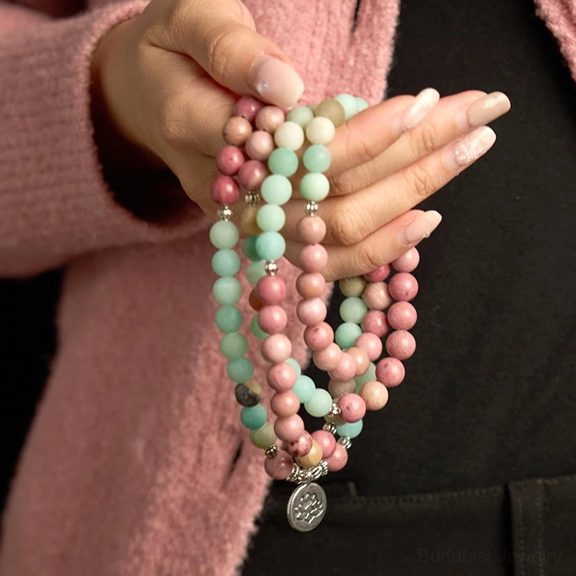 Hands holding 108 bead mala bracelet with rhodonite and amazonite beads and hanging silver lotus pendant charm