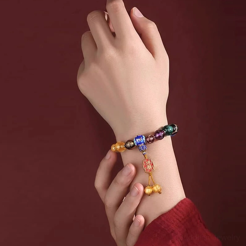 18-bead mala bracelet worn on hand showing dark-toned mixed incense ash liuli glass beads with enamel charm and golden bell tassels