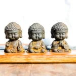 Three handcrafted Buddhist meditation Buddha statues in iron powder resin with different mudra hand gestures set displayed together on wooden tray