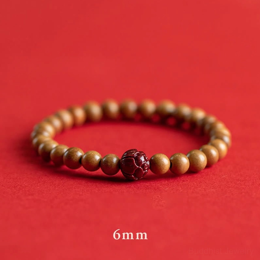 6mm peach wood and cinnabar lotus bracelet flat lay on red fabric, showing bead size marking