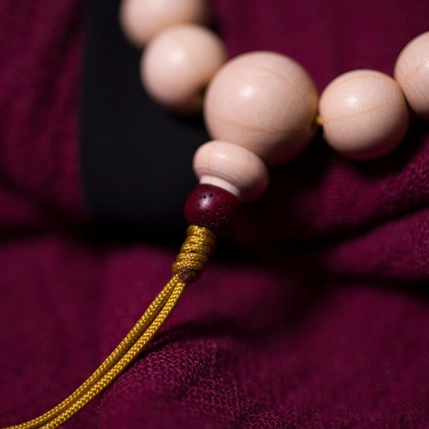 Abelia Biflora wood mala bracelet close-up detail showing red accent bead and golden tassel knot