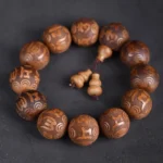 Abelia Biflora wood Buddhist prayer bracelet with engraved Om Mani Padme Hum mantra beads on dark background