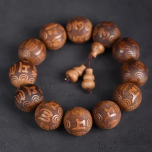 Abelia Biflora wood Buddhist prayer bracelet with engraved Om Mani Padme Hum mantra beads on dark background
