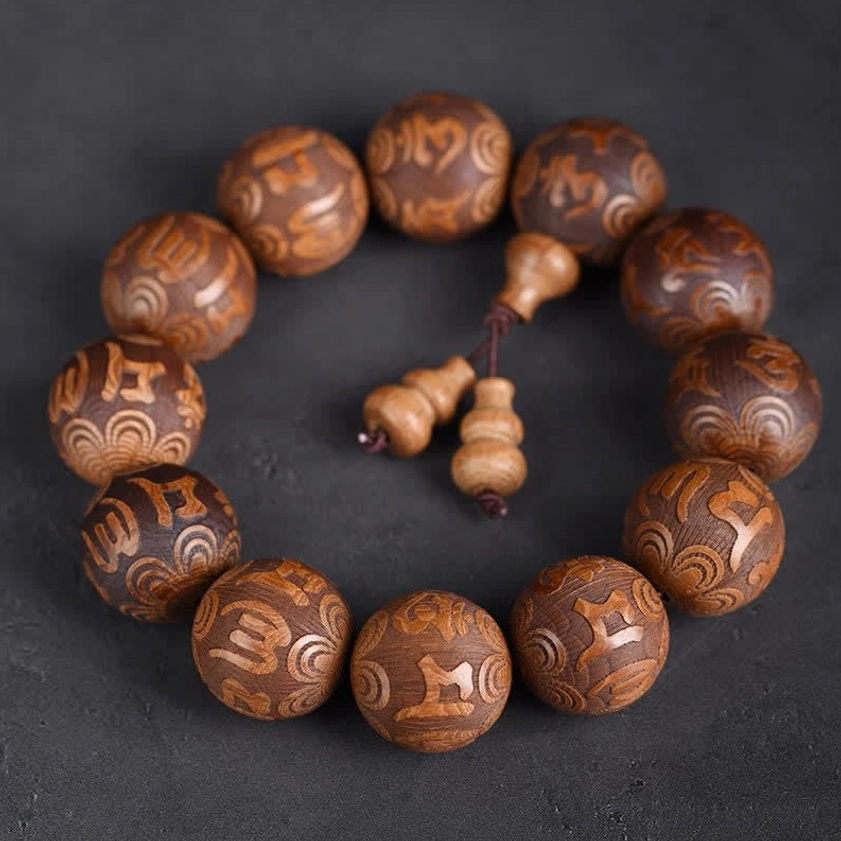 Abelia Biflora wood Buddhist prayer bracelet with engraved Om Mani Padme Hum mantra beads on dark background