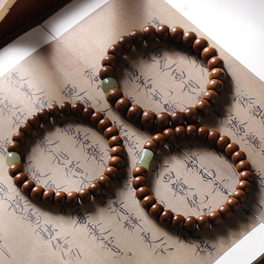 Three matching abelia wood hetian jade bamboo bead Buddhist bracelets arranged on ancient Chinese calligraphy paper