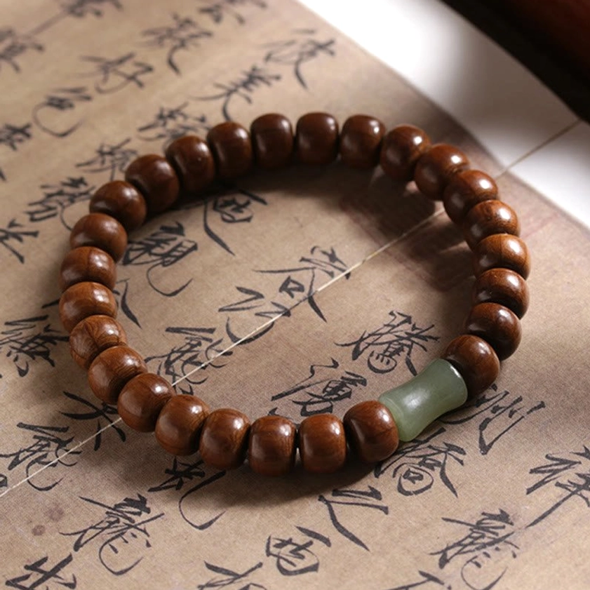 Single abelia wood hetian jade bamboo bead bracelet displayed flat on traditional Chinese calligraphy paper
