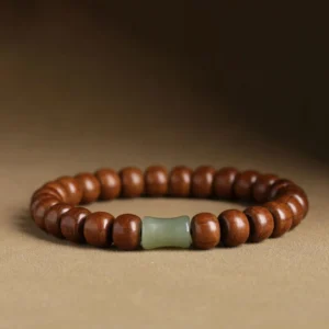 Abelia wood hetian jade bamboo bead bracelet with dark brown wooden beads and light green jade spacers on solid backdrop