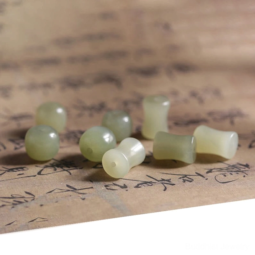 Loose light green bamboo-shaped jade beads and round abelia wood beads arranged overhead on calligraphy paper