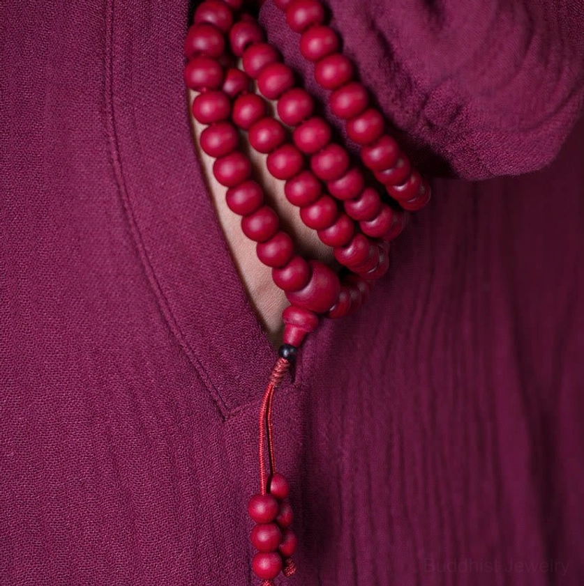 Red Abelia wood prayer beads worn on Buddhist robe with hanging tassel accent detail