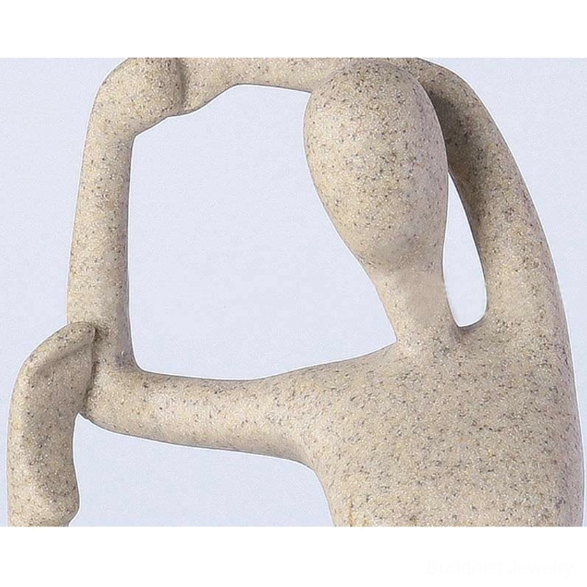 Close-up extreme angle view of abstract yoga stretch meditation figurine showing speckled beige resin matte texture