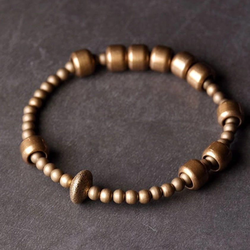 Vintage copper wealth balance bracelet overhead view with mixed bead sizes and central textured accent bead