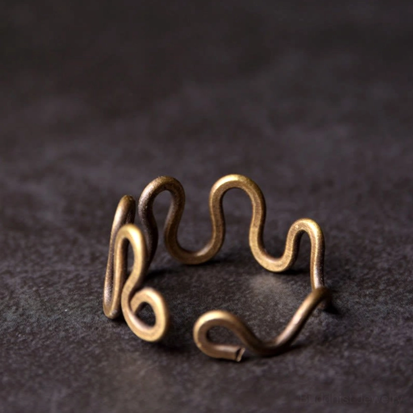 Curved brass spiritual ring overhead side view displaying elegant hollow wave pattern and adjustable open band