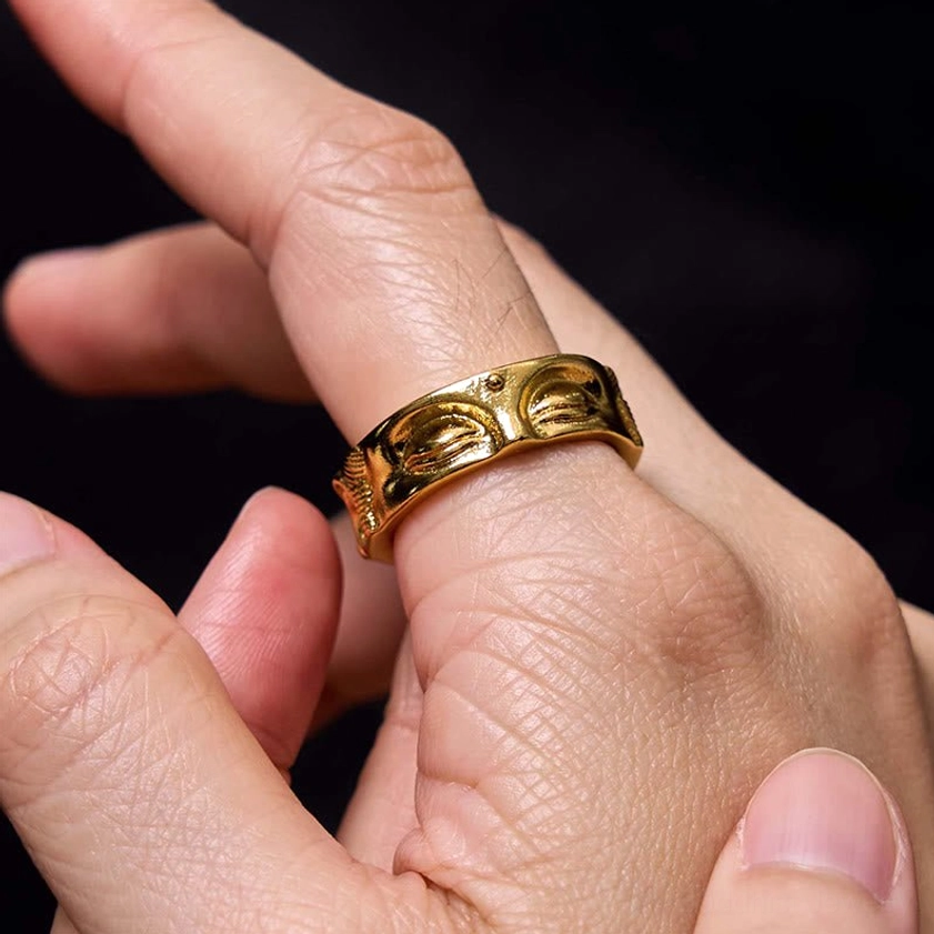 Close-up of Buddha's eye meditation copper ring worn on thumb showing adjustable open band fit and intricate carving details
