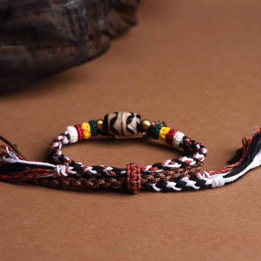 Woven Tibetan Buddhist bracelet with brown-black braided straps, adjustable knot closure, and tasseled ends