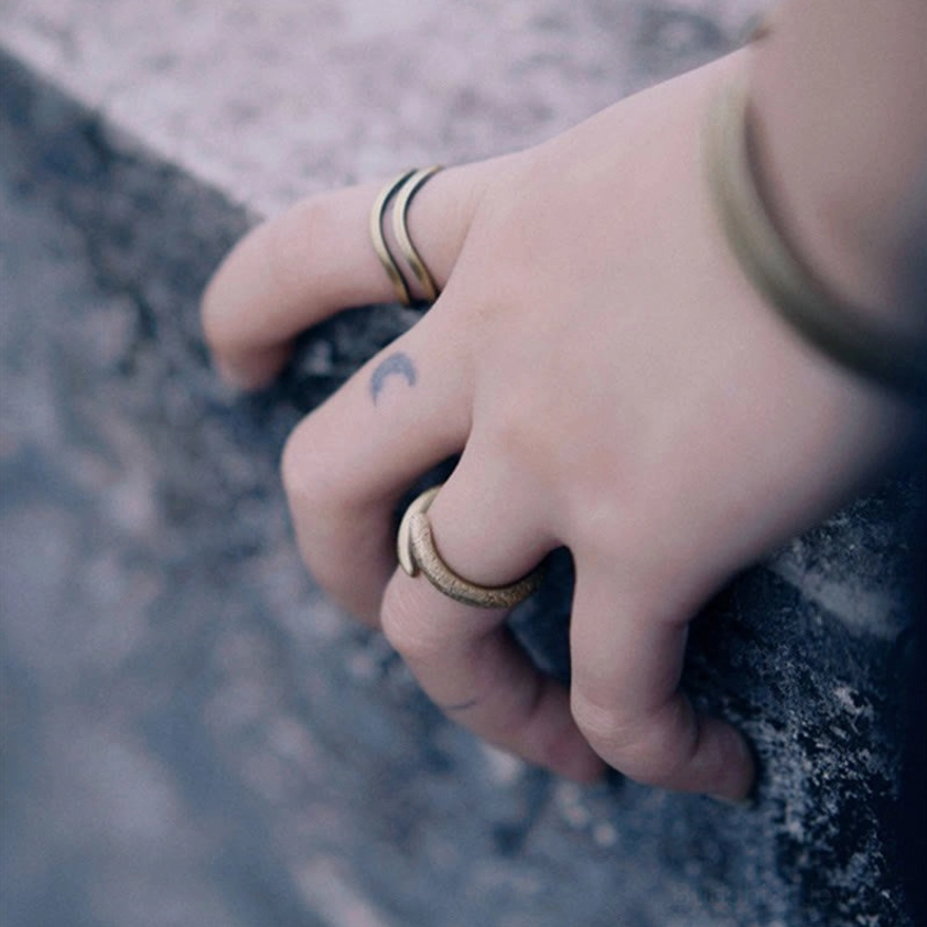 Multiple copper spiral wrap rings on hand outdoors, rocky background, casual lifestyle